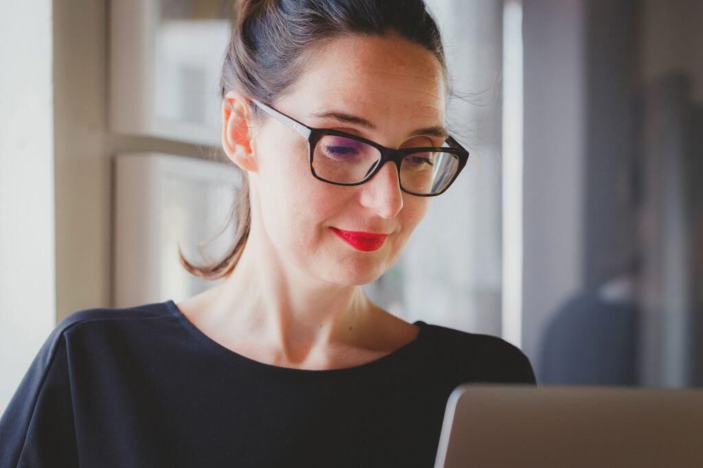 A smiling woman looking at her laptop screen