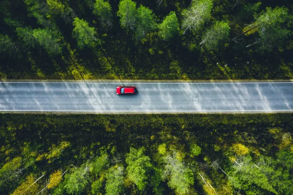 A car driving down a long, open road, surrounded by scenic views