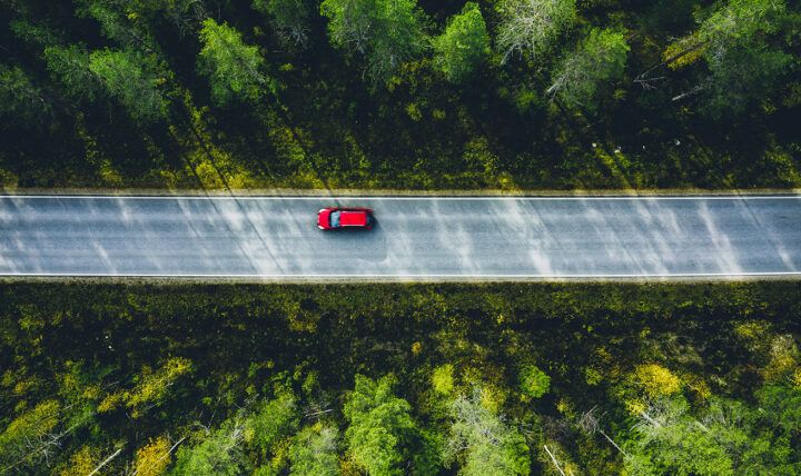 A car driving down a long, open road, surrounded by scenic views