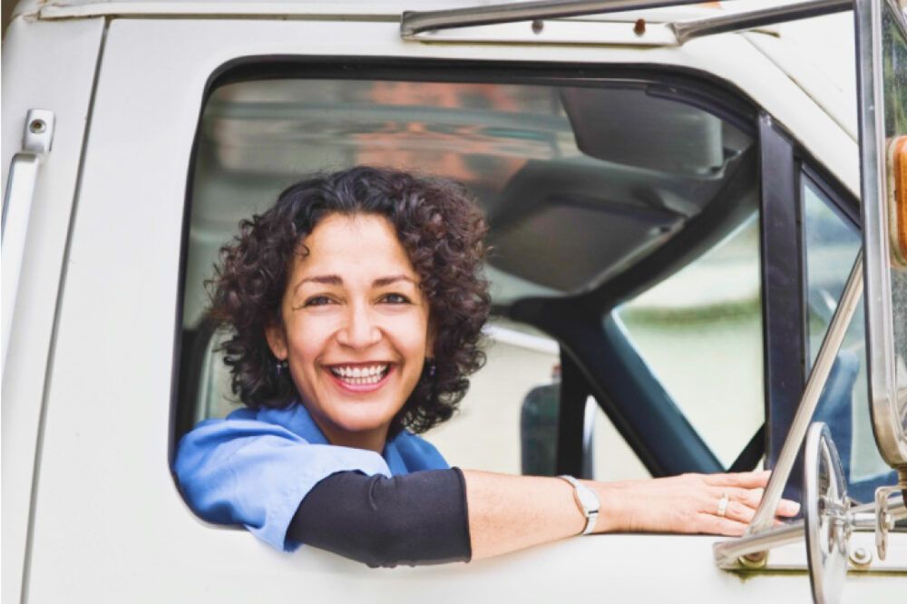 Een glimlachende vrachtwagenchauffeur die uit het raam kijkt
