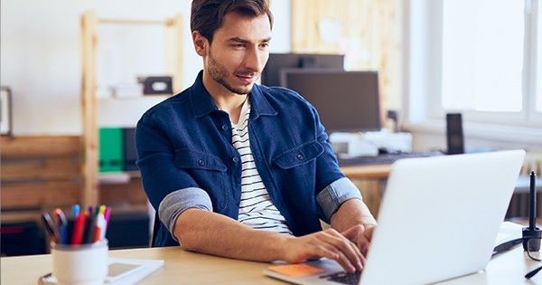 man typing on his laptop