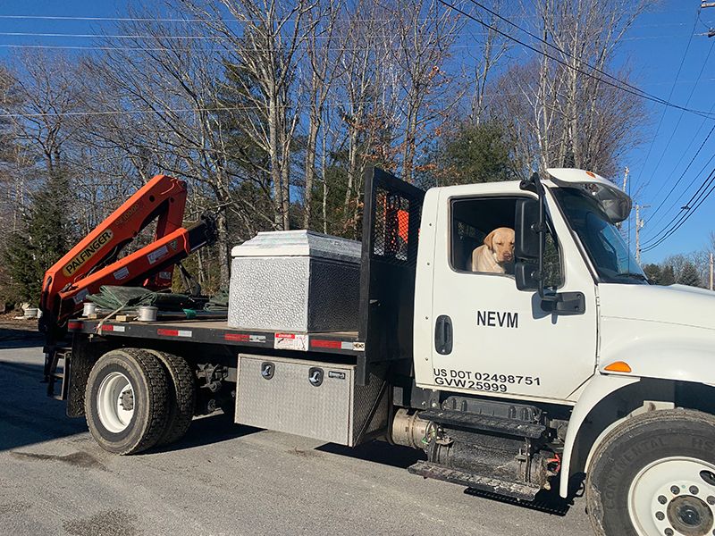 Tyler’s truck with an orange crane at the back and a silver vault in the bed of the truck