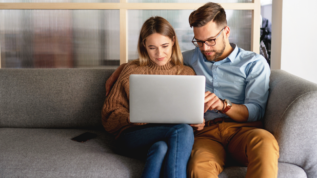 couple on couch looking at laptop