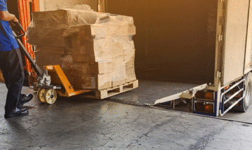 Trucker loading a pallet of goods into an empty cargo truck